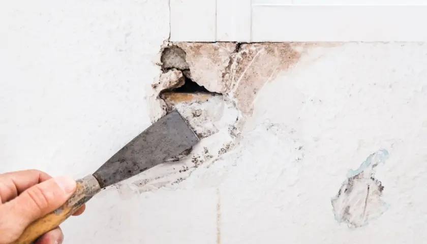 Mano con espátula preparando una pared para tapar agujeros.
