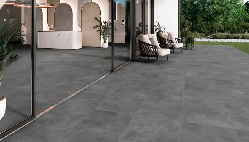 Amplia terraza con moderno suelo para terraza de gres porcelánico gris. Muebles de exterior y entrada acristalada.