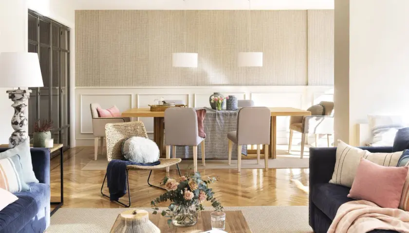 Un salón acogedor con sofás azules, una mesa de comedor de madera y una **beige color pared** con un patrón sutil.