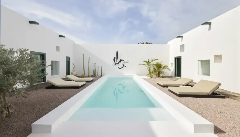 Patio minimalista con piscina, tumbonas y cactus. Ideas para decorar un patio con piscina y crear un oasis moderno.