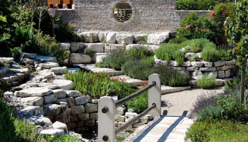 Un hermoso jardín con cascadas de piedra y plantas aromáticas, ideal para decorar jardín con piedras y crear un oasis de paz.