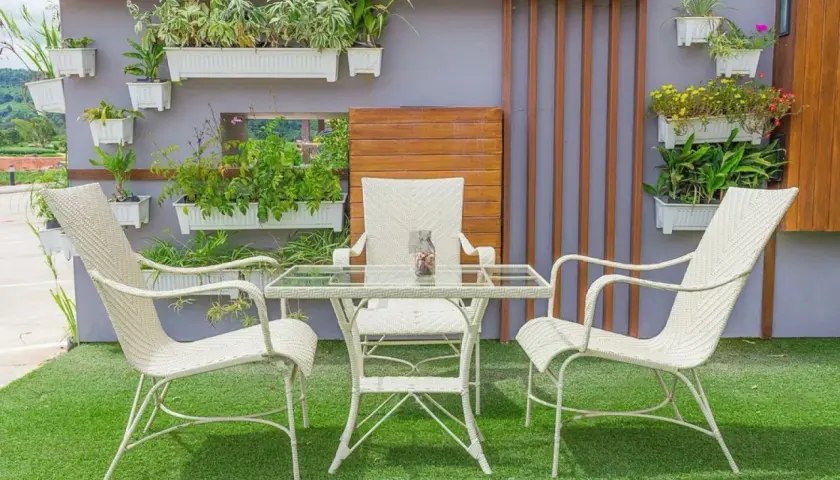 Un oasis verde en patios pequeños con césped artificial. Muebles blancos y plantas colgantes crean un rincón acogedor.