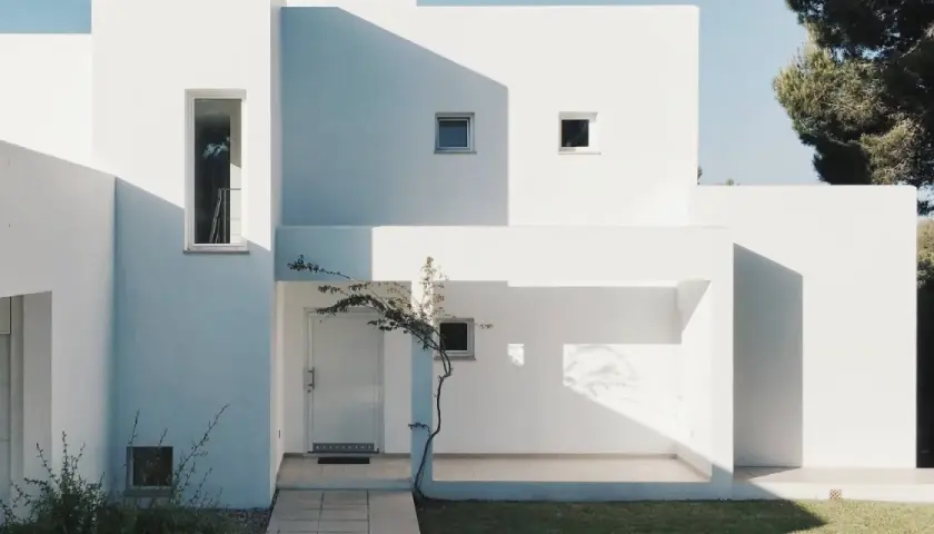 Fachada blanca moderna con sombras marcadas. La mejor pintura para fachadas exteriores protege y embellece esta arquitectura minimalista.