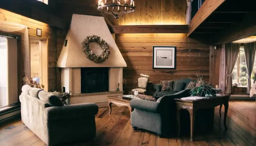 Salón rústico con chimenea de obra decorada con corona de hojas. Sofás cómodos y suelo de madera invitan a relajarse.
