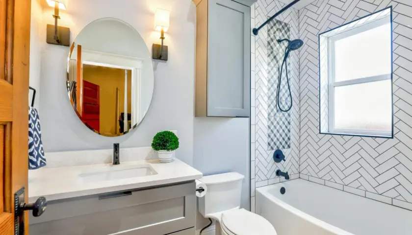 Moderno baño con lavabo, inodoro y una bañera o ducha con azulejos de espiga.