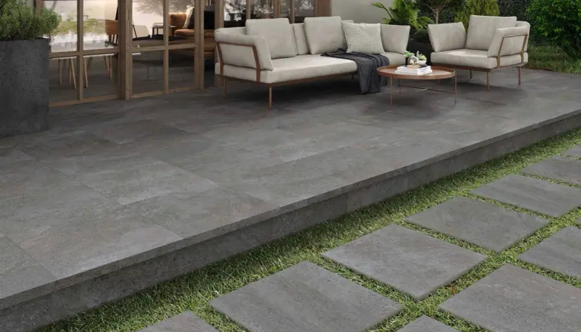 Terraza moderna con suelo de baldosas grises, ideal para pintar suelo terraza exterior. Muebles de exterior y plantas crean un oasis.