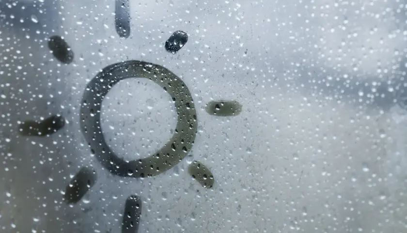 Sol dibujado en una ventana con gotas de condensación. Consejos para saber como evitar que las ventanas sudan en invierno.