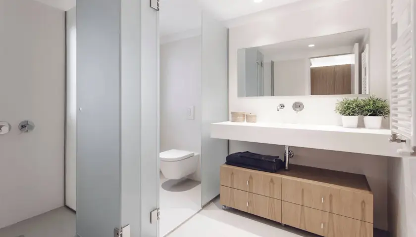 Baños modernos con ducha, inodoro y lavabo con mueble de madera.