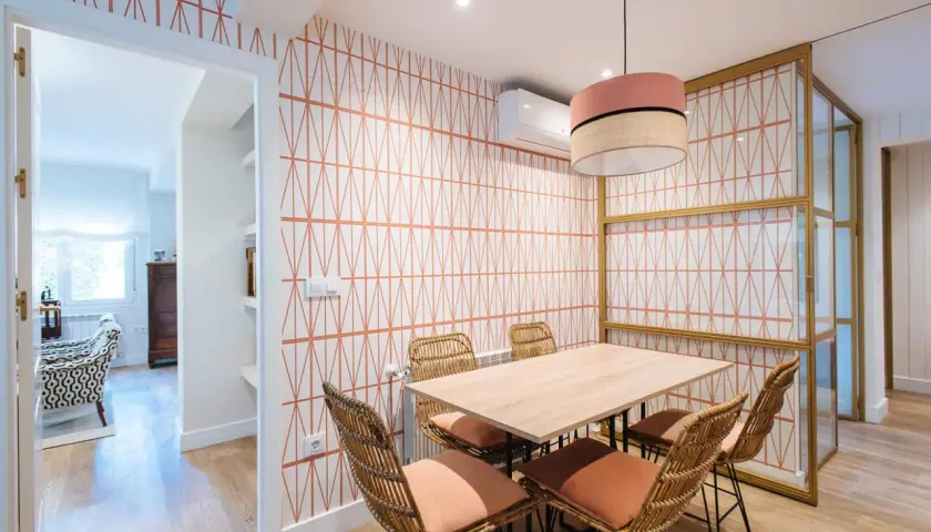 Comedor con papel pintado de rombos naranjas, mesa de madera y sillas de mimbre. ¡Una idea genial para saber como poner papel pintado!