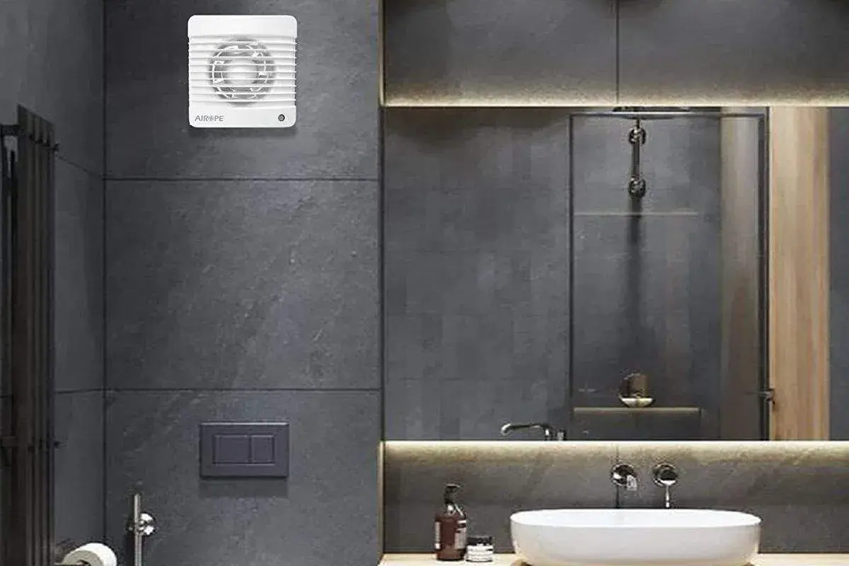 Extractor de baño blanco instalado en pared de azulejos grises.