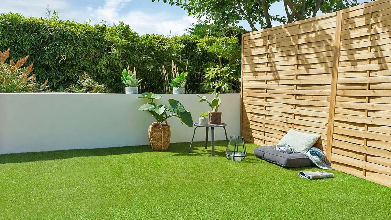 Terraza con césped artificial verde vibrante, plantas en macetas, un banco y una valla de madera.