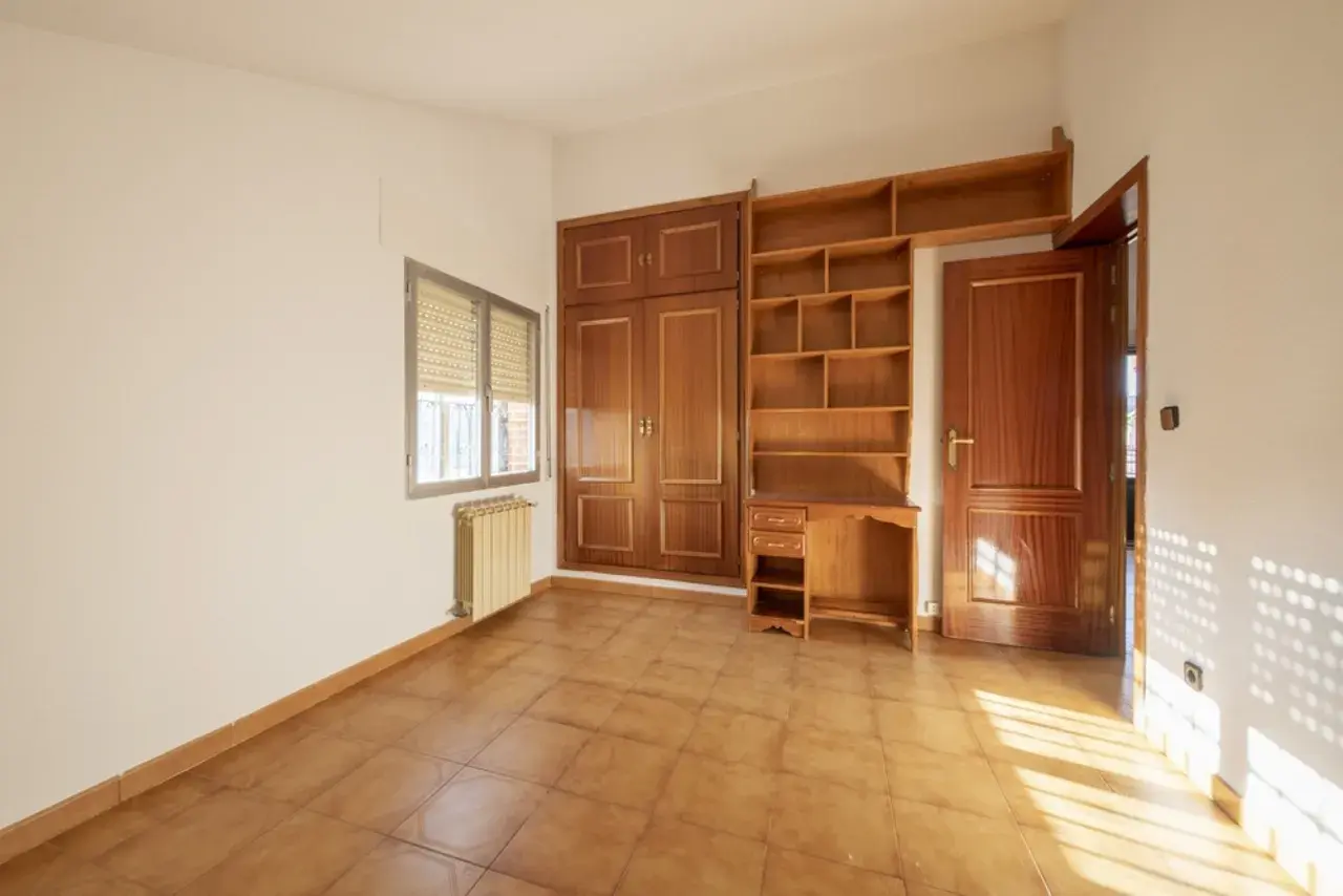 Habitación con armario y estanterías de madera. Las puertas sapelly cambiar color con la luz, creando un ambiente cálido.
