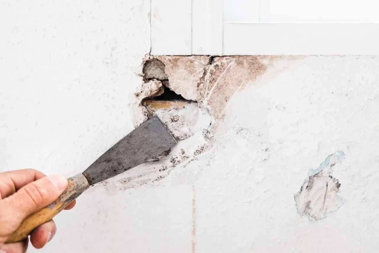 Mano con espátula preparando una pared para tapar agujeros.