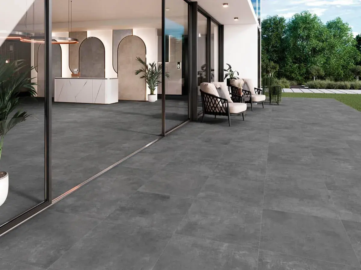 Amplia terraza con moderno suelo para terraza de gres porcelánico gris. Muebles de exterior y entrada acristalada.