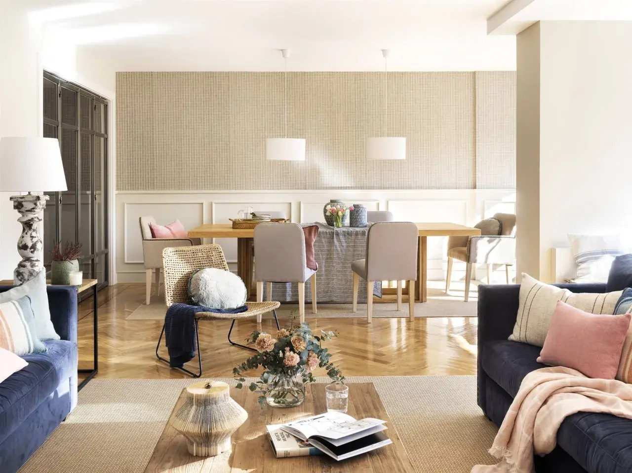 Un salón acogedor con sofás azules, una mesa de comedor de madera y una **beige color pared** con un patrón sutil.
