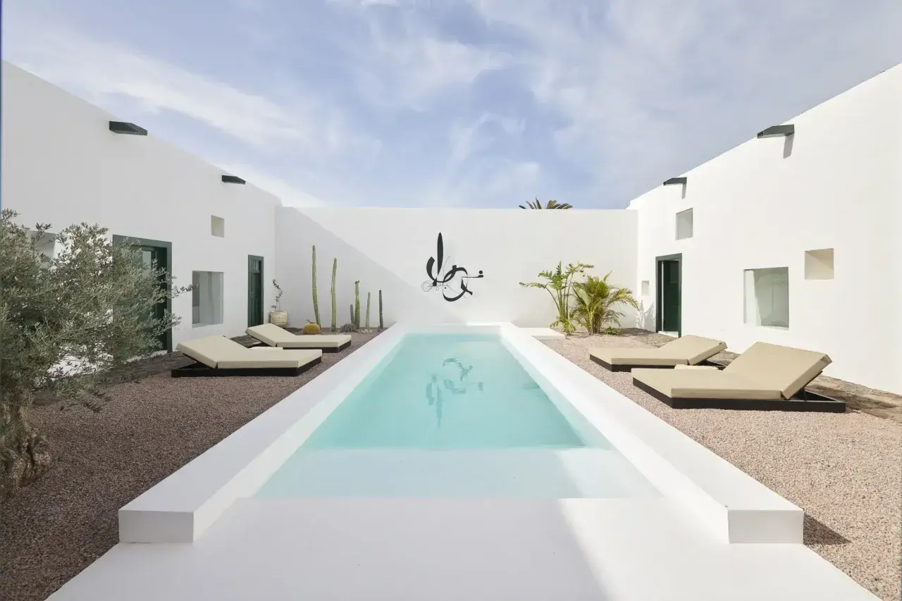 Patio minimalista con piscina, tumbonas y cactus. Ideas para decorar un patio con piscina y crear un oasis moderno.