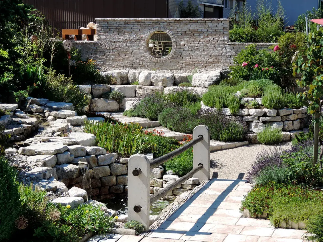 Un hermoso jardín con cascadas de piedra y plantas aromáticas, ideal para decorar jardín con piedras y crear un oasis de paz.