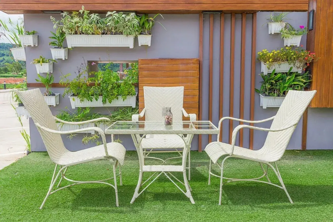 Un oasis verde en patios pequeños con césped artificial. Muebles blancos y plantas colgantes crean un rincón acogedor.