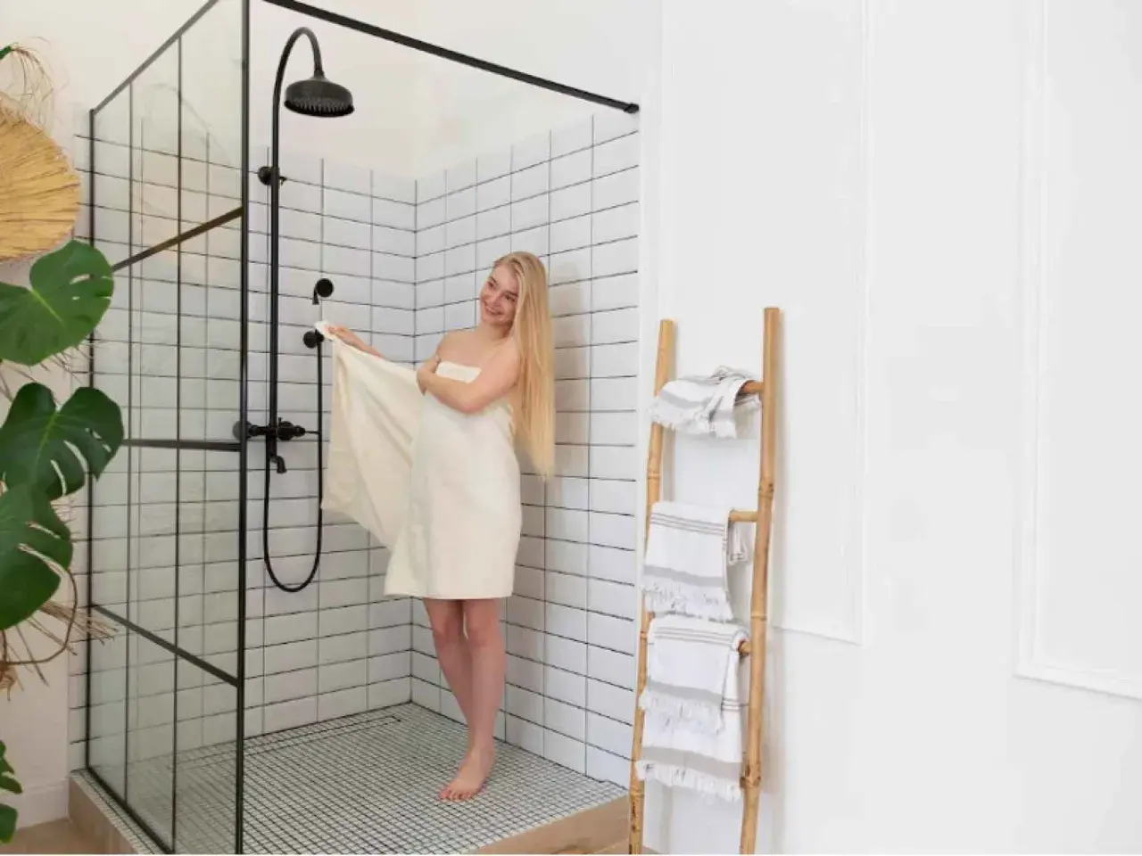 Mujer rubia envuelta en toalla junto a mampara de ducha moderna. Explora los tipos de mamparas de ducha para tu baño.