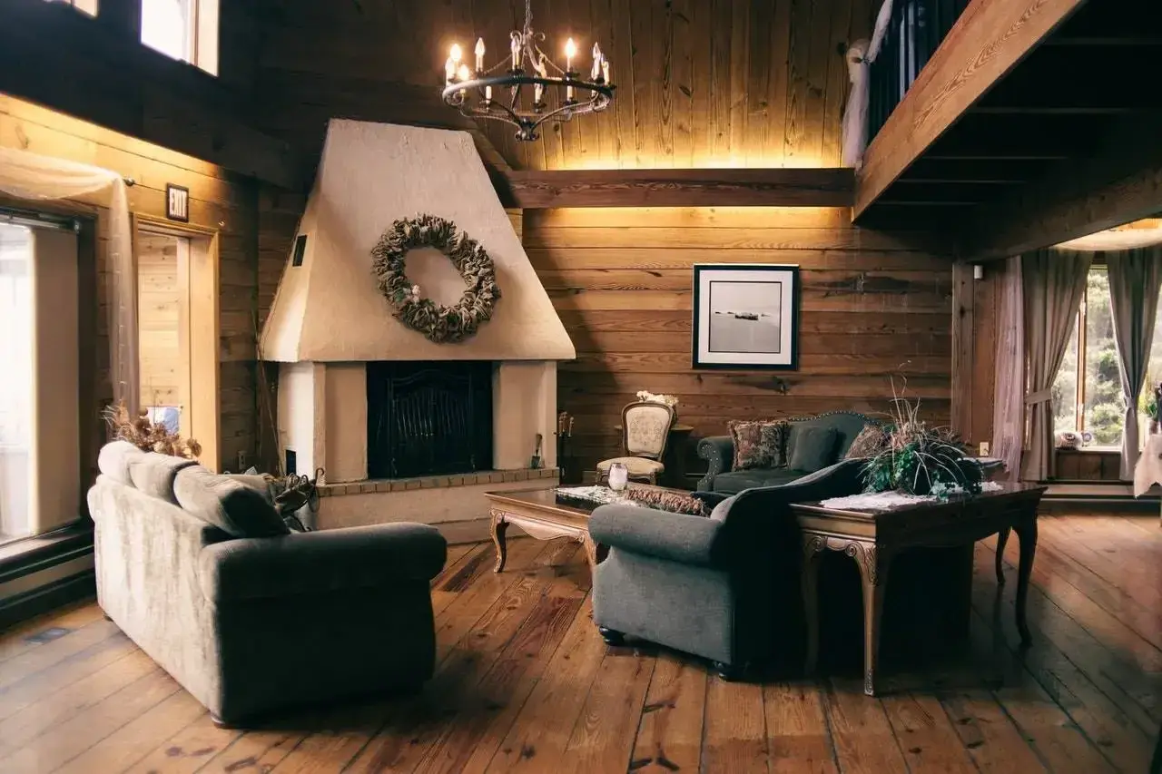Salón rústico con chimenea de obra decorada con corona de hojas. Sofás cómodos y suelo de madera invitan a relajarse.