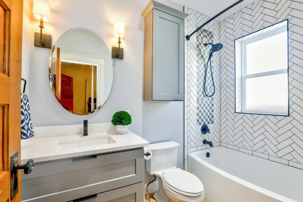 Moderno baño con lavabo, inodoro y una bañera o ducha con azulejos de espiga.