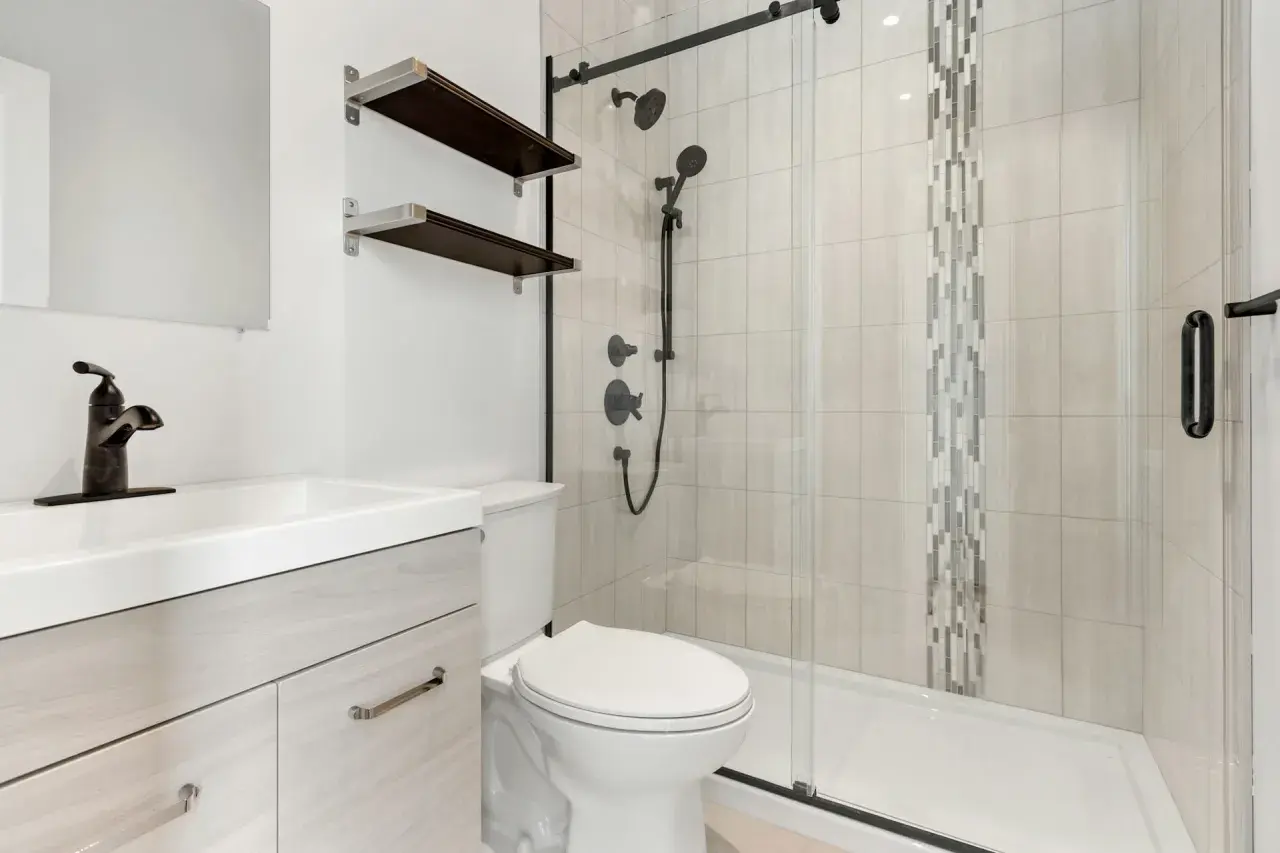 Baño moderno con lavabo, inodoro y plato de ducha de resina. Ideal para aprender como reparar un plato de ducha de resina.