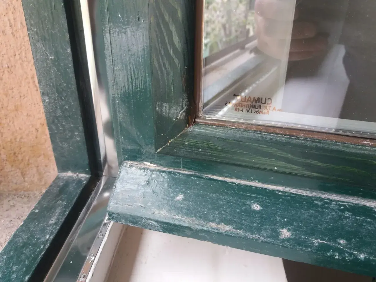 Detalle de marcos de madera antiguos pintados de verde, mostrando el proceso para aislar ventanas antiguas de madera y mejorar su eficiencia.
