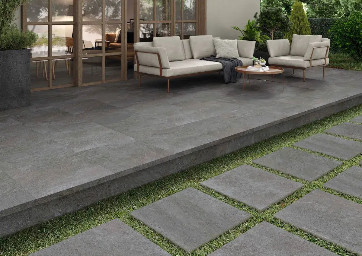 Terraza moderna con suelo de baldosas grises, ideal para pintar suelo terraza exterior. Muebles de exterior y plantas crean un oasis.
