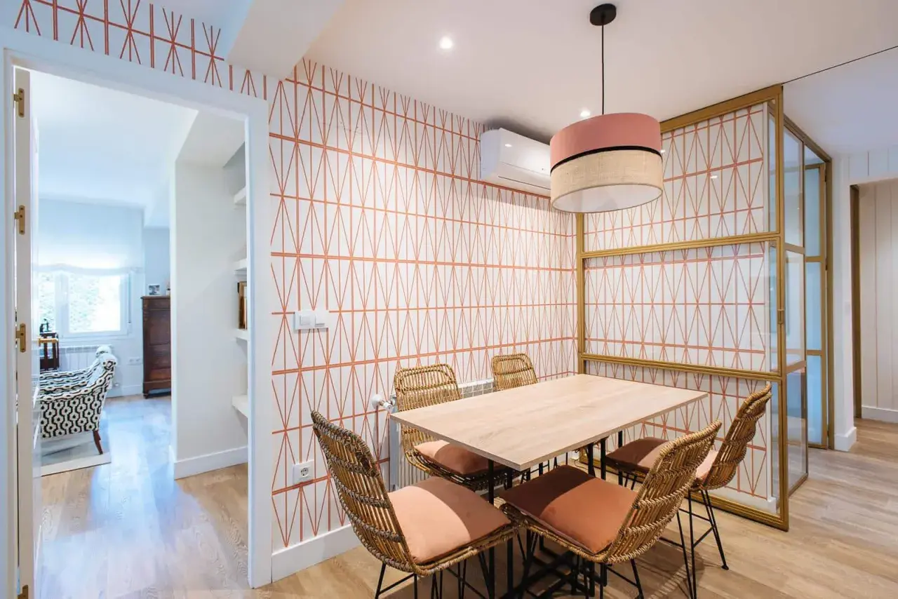 Comedor con papel pintado de rombos naranjas, mesa de madera y sillas de mimbre. ¡Una idea genial para saber como poner papel pintado!