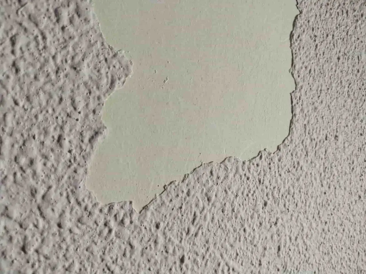 Detalle de pared con gotel&eacute; descascarillado, mostrando c&oacute;mo quitar gotele para renovar la superficie.