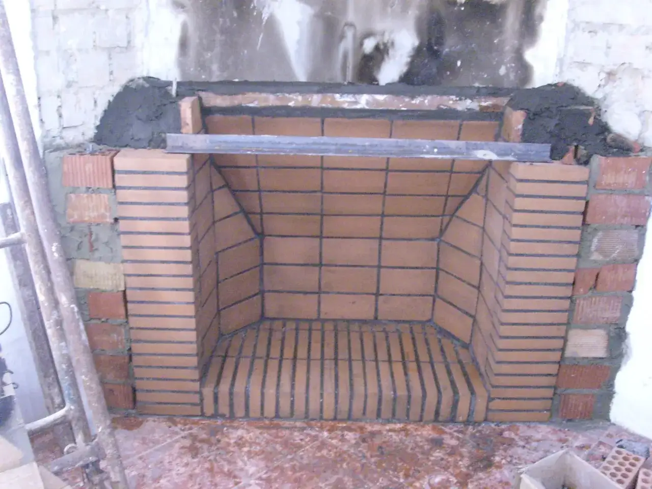Construcción de chimenea de obra con ladrillos refractarios. Se aprecian los primeros pasos para como hacer una chimenea de obra, con la base y paredes en proceso.