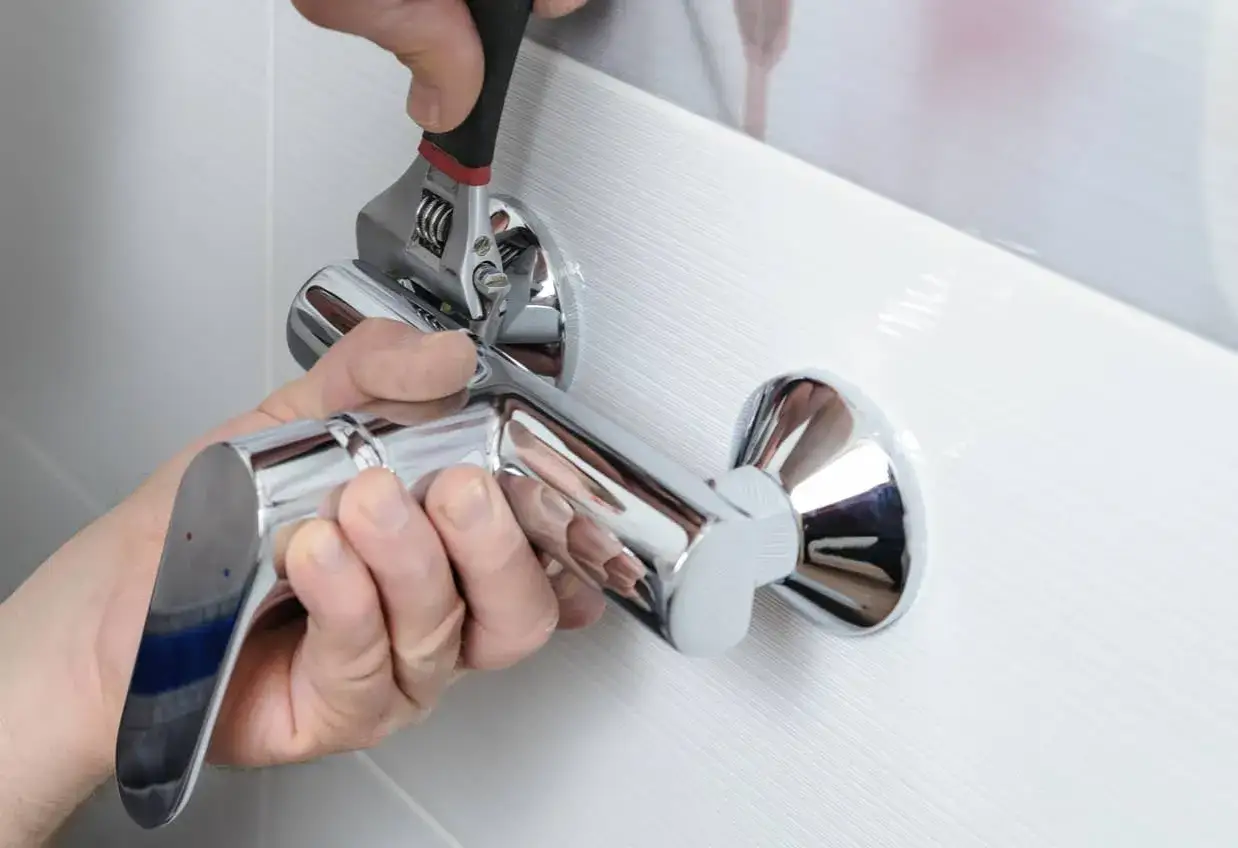 Man usando una llave inglesa para cambiar grifo ba&ntilde;era.
