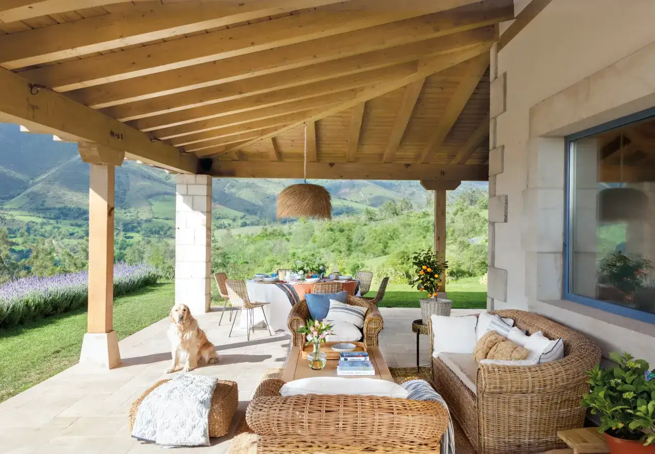 Porches sencillos y bonitos con muebles de mimbre, un perro y vistas a un paisaje verde.