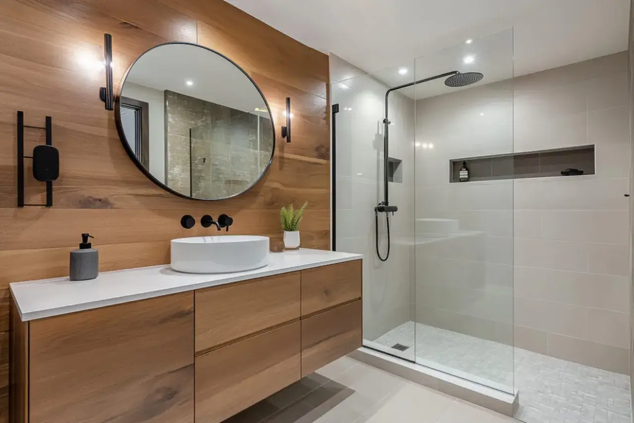 Ba&ntilde;o moderno con lavabo sobre encimera, mueble de madera y una amplia ducha de cristal.