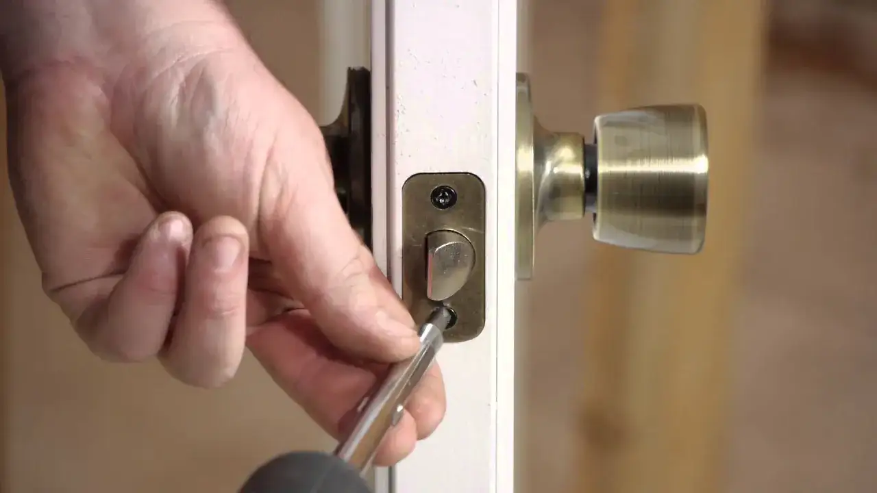 Mano desatornillando la placa de la cerradura de una puerta interior. Gu&iacute;a para como desmontar una cerradura de puerta interior.