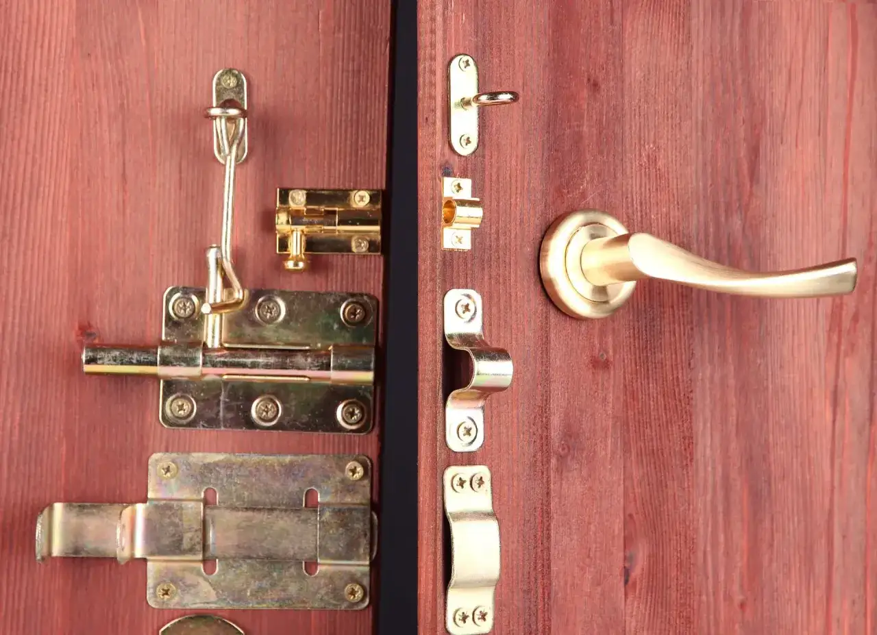 Detalle de varios tipos de pestillos para puertas de madera, incluyendo cerrojos deslizantes y un picaporte dorado.