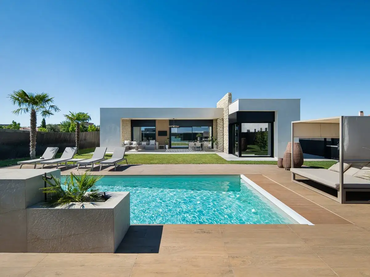 Ideas para decorar un patio con piscina: tumbonas, palmeras y una caba&ntilde;a moderna crean un oasis de relax.