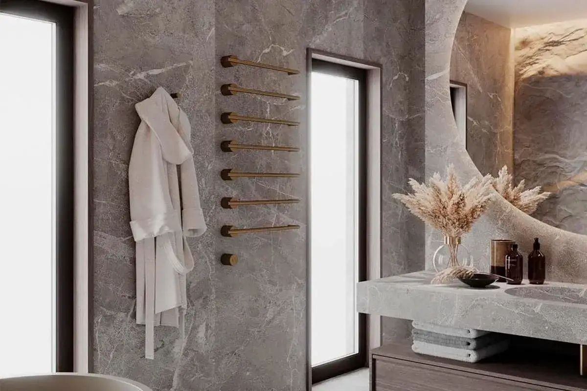 Elegante baño con azulejos de mármol gris, toallero dorado y albornoz blanco. Un toque moderno para pintar azulejos baño.