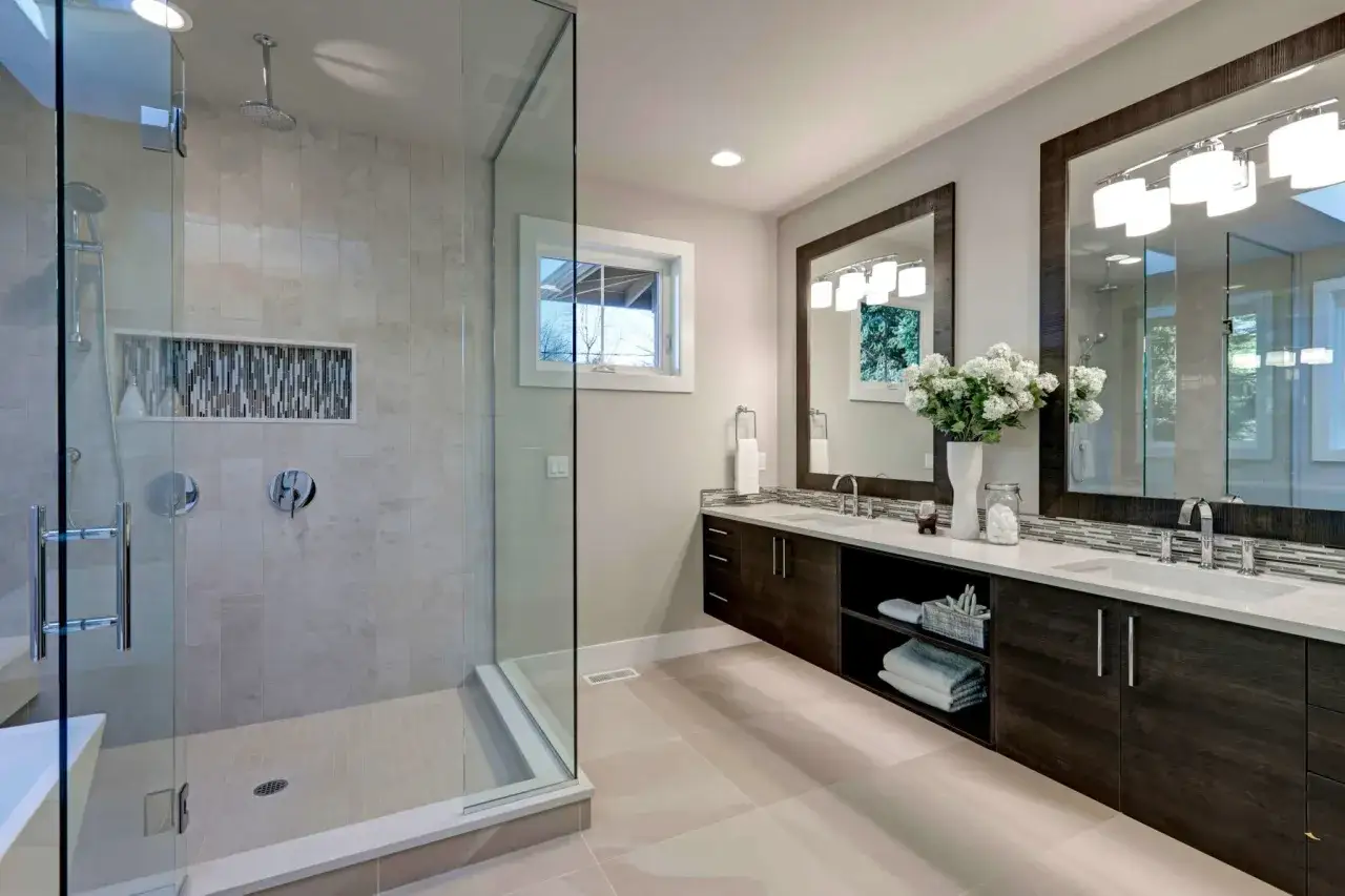 Elegantes ba&ntilde;os modernos con ducha de cristal, doble lavabo y espejos amplios.