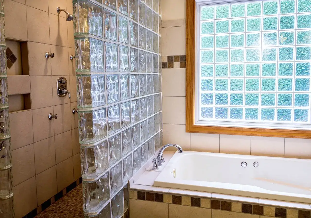 Duchas con paves de vidrio separan la zona de ducha de la ba&ntilde;era. La luz se filtra a trav&eacute;s de la ventana de paves.
