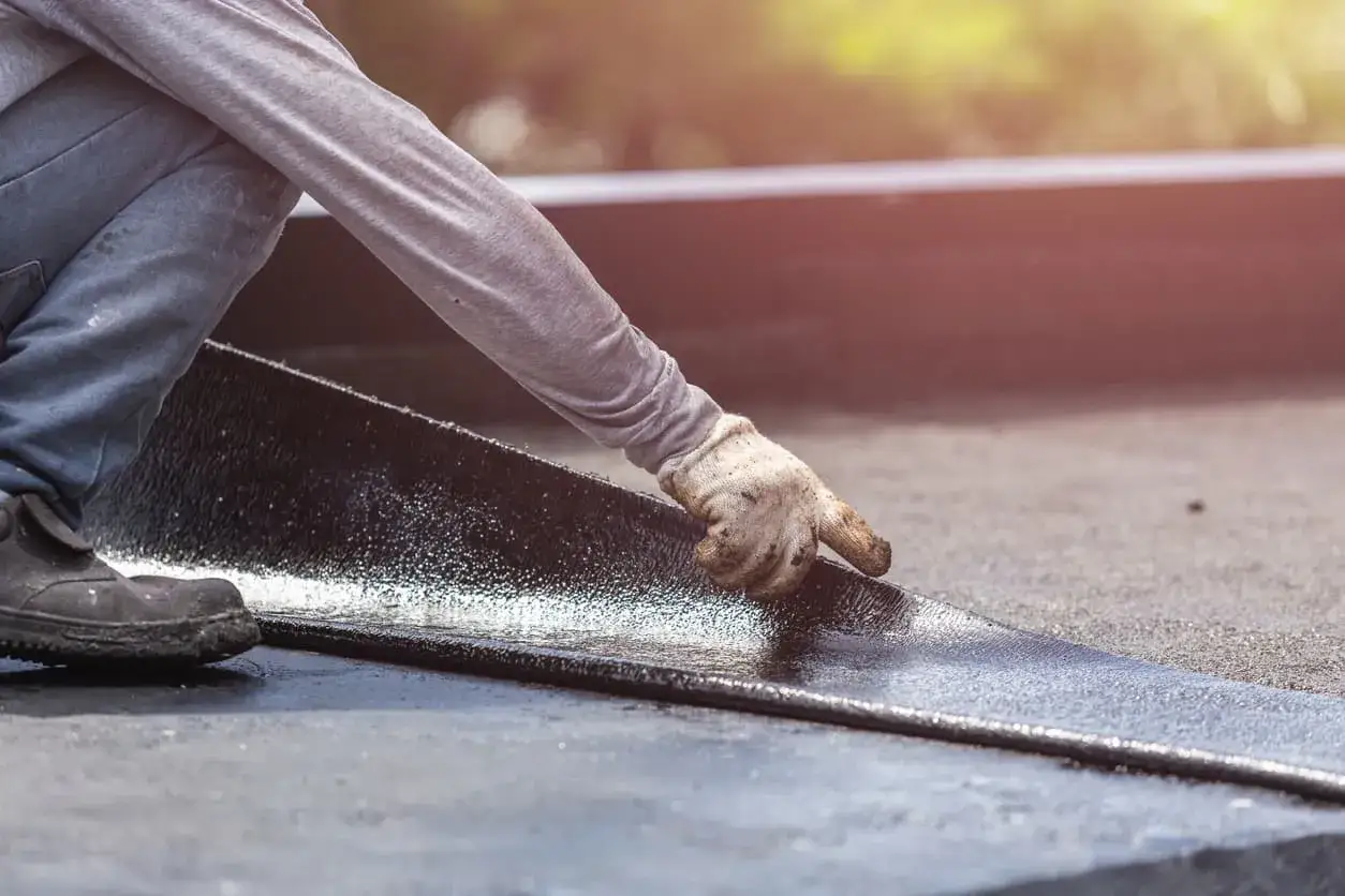Trabajador instala tela asf&aacute;ltica para impermeabilizar terraza.