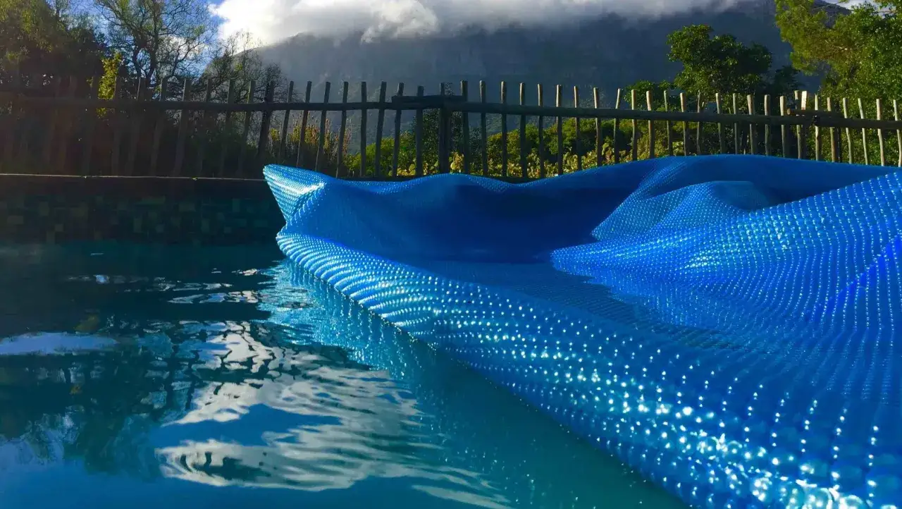 Cubierta azul burbujeante en piscina, ideal para saber como calentar el agua de la piscina de forma natural.