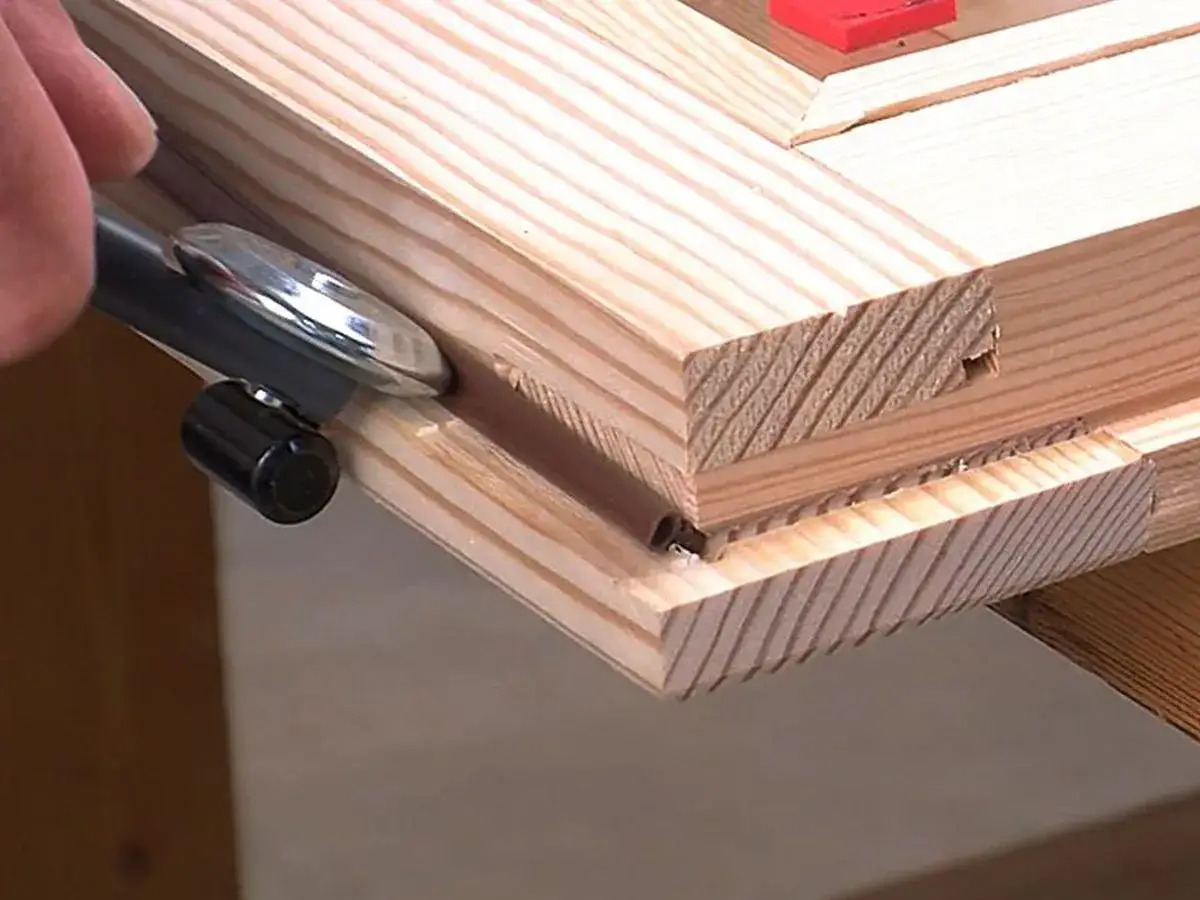Herramienta para aislar ventanas antiguas de madera, aplicando sellador en la ranura de un marco de pino.