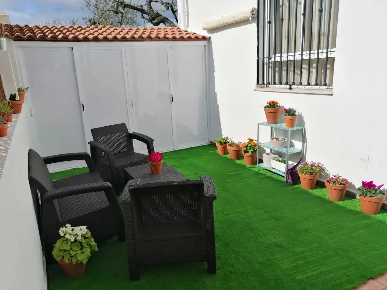 Acogedores patios peque&ntilde;os con c&eacute;sped artificial, muebles de mimbre y macetas coloridas.