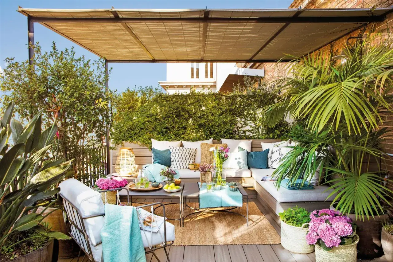 Un oasis verde y acogedor, perfecto para la decoracion terrazas pequeñas. Sofá, mesas bajas, plantas exuberantes y textiles crean un rincón de ensueño.