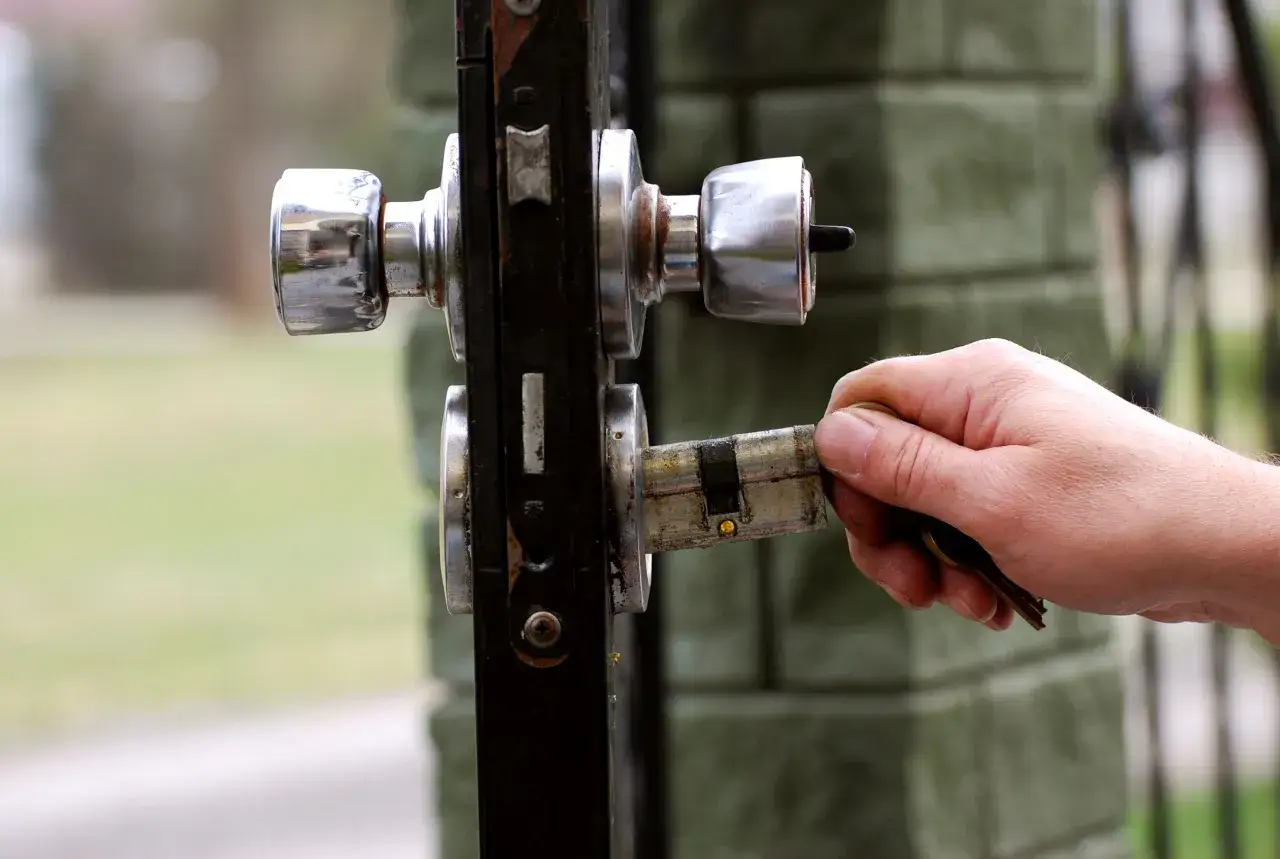 Mano insertando llave en cerradura de puerta, mostrando diferentes tipos bombin cerradura.